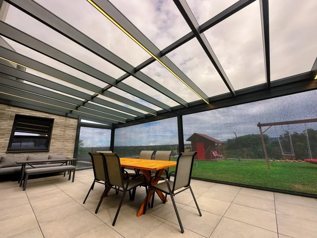 Pergola s pevnou skleněnou střechou a bočními screenovými roletami